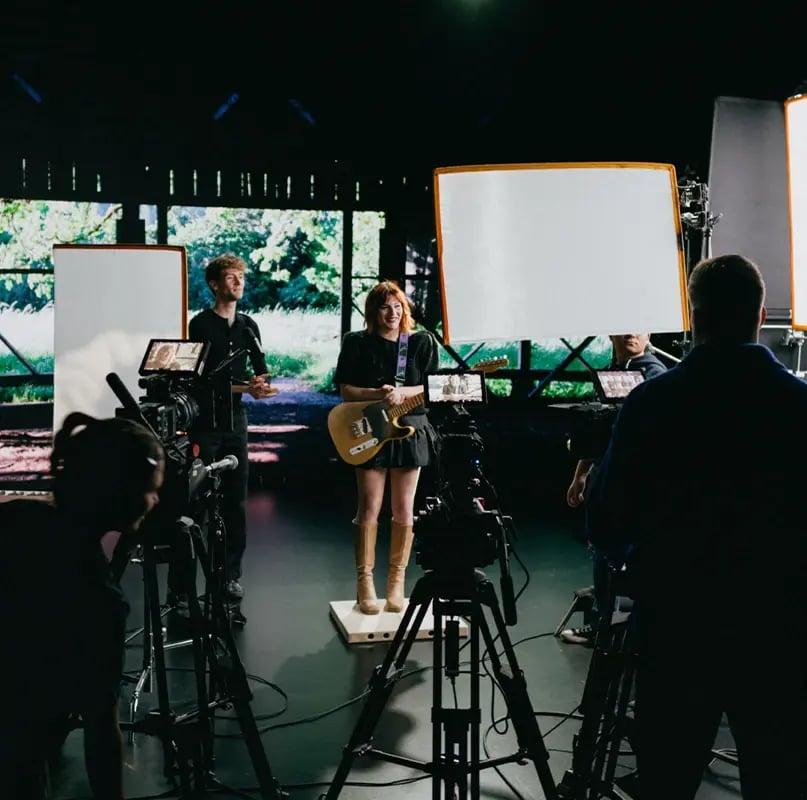 A musician stands in front of a 2D plate on an LED virtual production stage