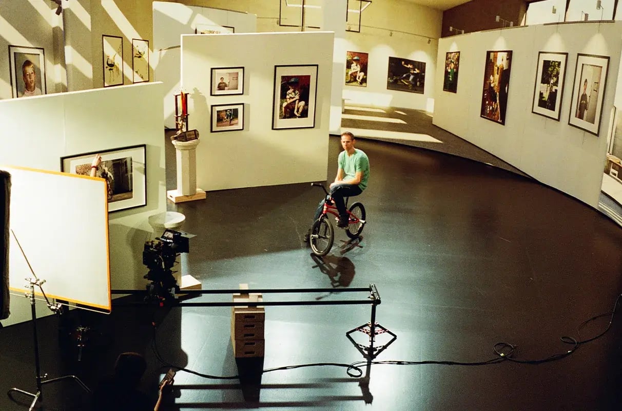 A BMX biker sits on a virtual production set depicting a museum while a cinema camera on a dolly films him