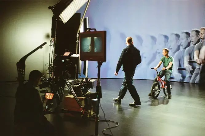 A director walks in front of a BMX biker while filming in a virtual production LED volume