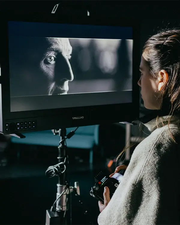 A film crew member inspects the shot on a monitor