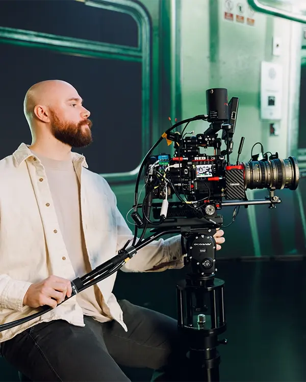 A cinematographer operating a RED cinema camera on a doorway dolly at a virtual production studio