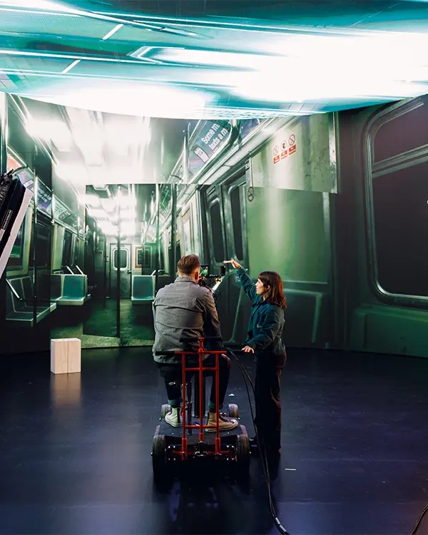 A cinematographer and first AC operating a cinema camera on a doorway dolly. The utilization of Unreal Engine virtual environments and camera tracking leaves a frustum on the LED wall
