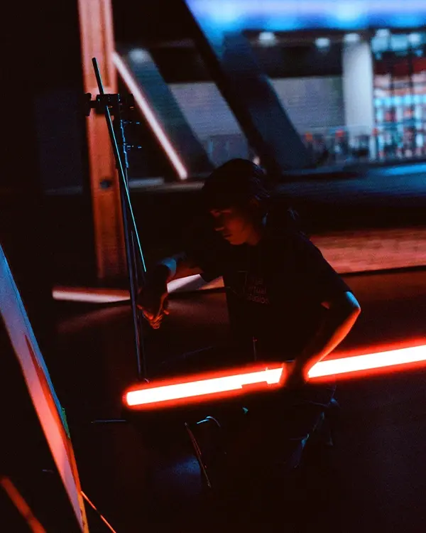 A grip adjusts a tube light on an LED Virtual production stage