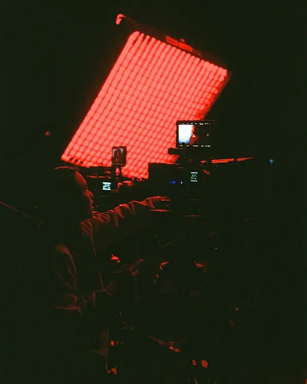 A cinematographer adjusts the camera in front of an Aputure infinimat light on an LED virtual production stage