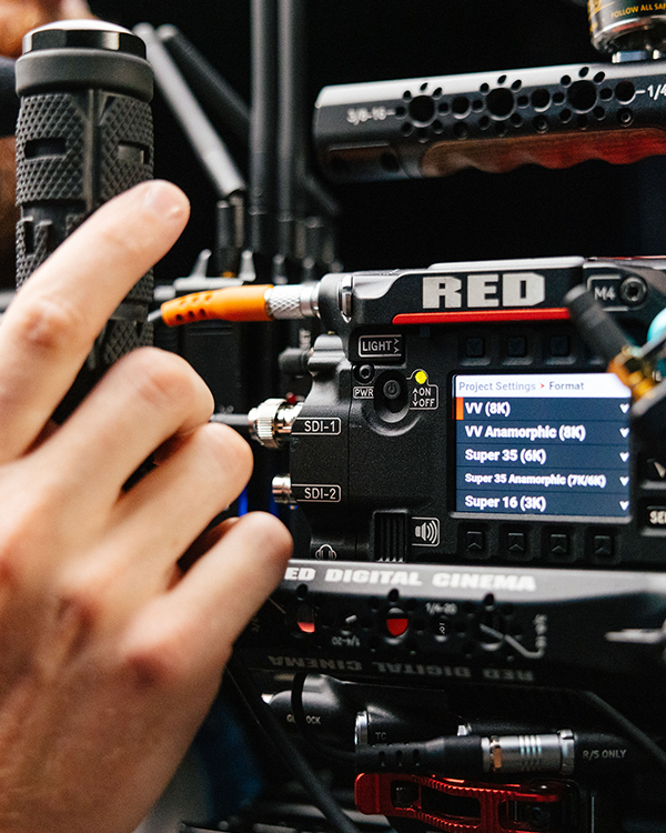 A camera operator holds a RED V-Raptor camera on a production set